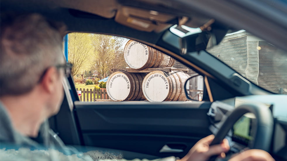 Interior shot of the Bigster SUV looking through the passenger window at barrels with The Enlgish Whiskey Co branding
